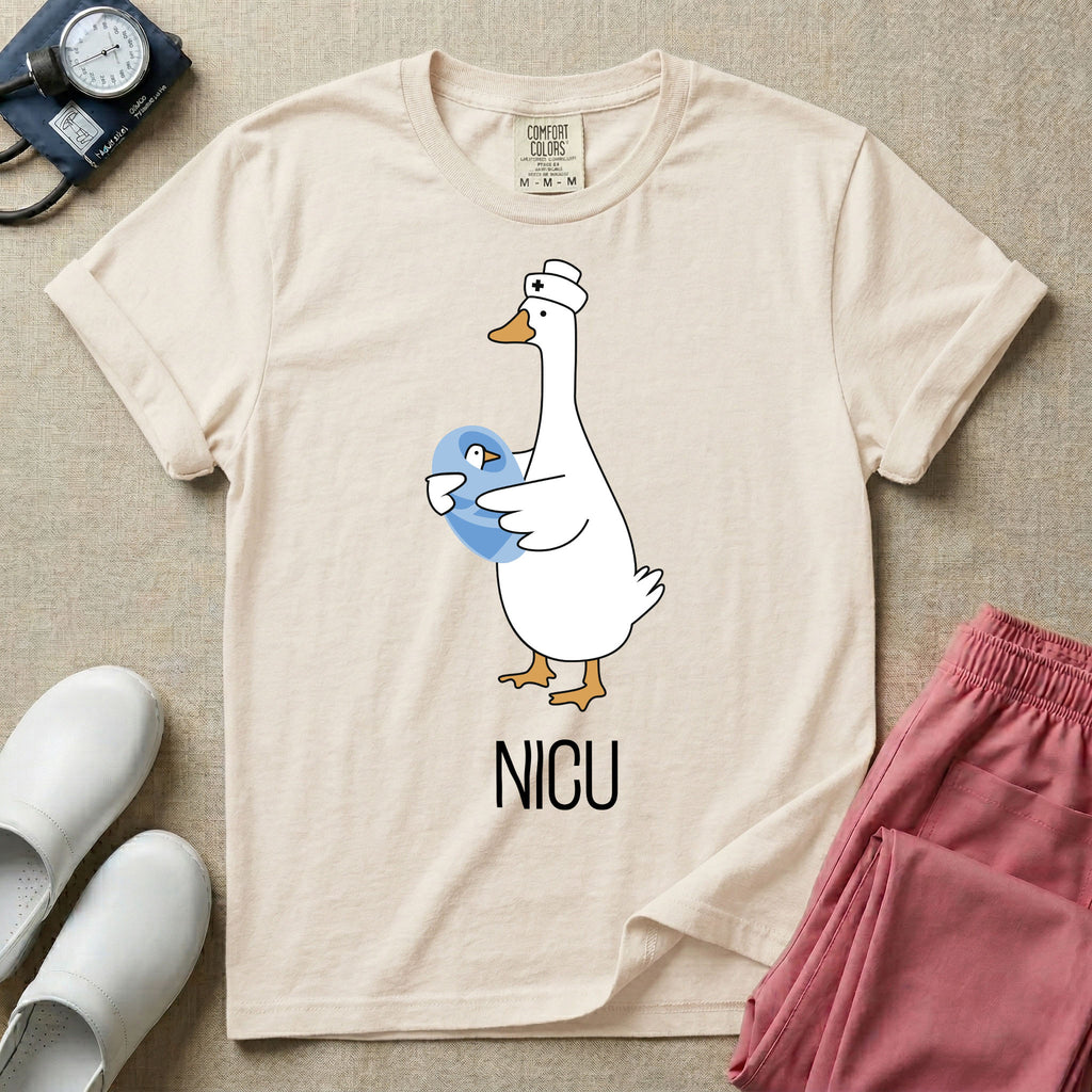A t-shirt featuring an illustration of a white silly goose wearing a nurse's cap and holding a baby goose swaddled in a blue blanket, with the text NICU printed below.