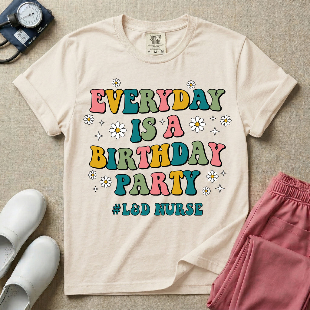 A retro graphic tee for labor and delivery nurses featuring bubble lettering that reads "EVERYDAY IS A BIRTHDAY PARTY #L&D NURSE" surrounded by small daisies and stars.