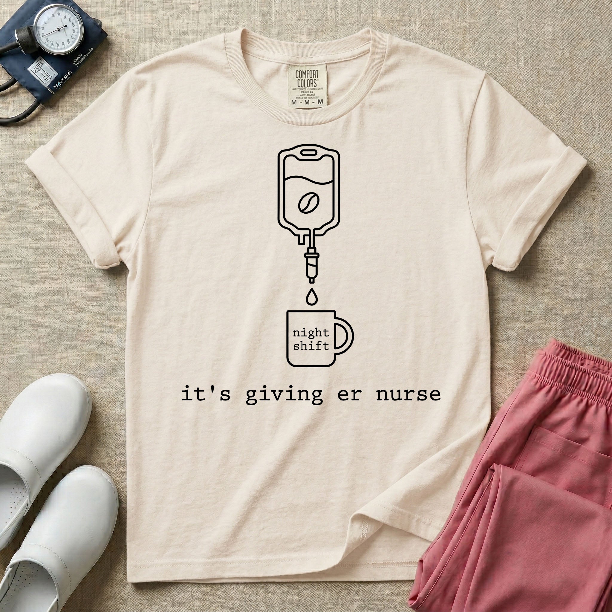 A funny minimalist ER nursing t-shirt featuring a white line drawing of an IV bag containing a coffee bean dripping into a mug labeled "night shift", sitting above the lower-case typewriter text "it's giving er nurse".