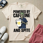 A humorous graphic for general nursing featuring an illustration of a skeleton wearing a green scrub cap and dark blue scrubs, holding a large white coffee cup with a yellow biohazard symbol, with the stacked text 'POWERED BY CAFFEINE' above it and 'AND SPITE' below it.
