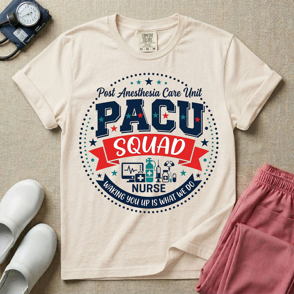 A t-shirt featuring a circular badge design with the text PACU SQUAD in block letters, medical icons like a heart monitor and stethoscope, and the phrase Waking You Up Is What We Do.