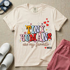 A t-shirt featuring the text Tiny Humans are my favorite in colorful retro bubble letters decorated with daisies, sparkles, and red hearts with a small NICU heart logo at the bottom.