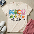 A cute t-shirt for NICU nurses featuring the text "NICU nurse" where the letters are designed with ocean elements like waves, seaweed, and a jellyfish, surrounded by under the sea creatures including a sea turtle, tropical fish, pufferfish, and starfish.
