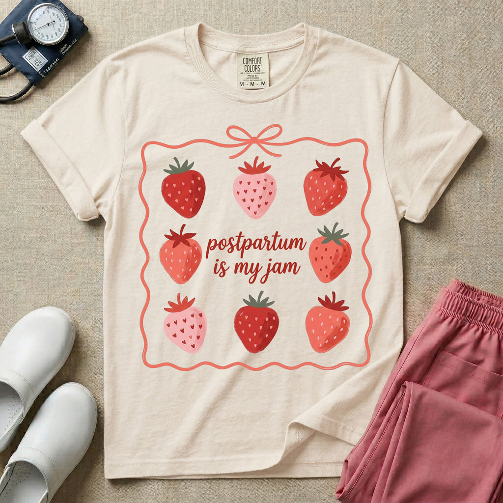 A funny and cute postpartum nursing t-shirt featuring the pun text "postpartum is my jam" surrounded by a graphic of red and pink strawberries, enclosed in a decorative wavy border with a bow at the top.