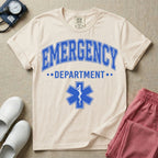 A classic varsity-style t-shirt for emergency room nurses featuring the word "EMERGENCY" in a large, arched blue collegiate font above the word "DEPARTMENT", centered over a blue Star of Life medical symbol.