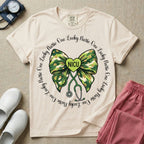 A graphic for a Neonatal Intensive Care Unit featuring a green camouflage bow with a stethoscope dangling from the bottom, a green heart in the center reading 'NICU', and the phrase 'One Lucky Nurse' repeating in a circle around the design.