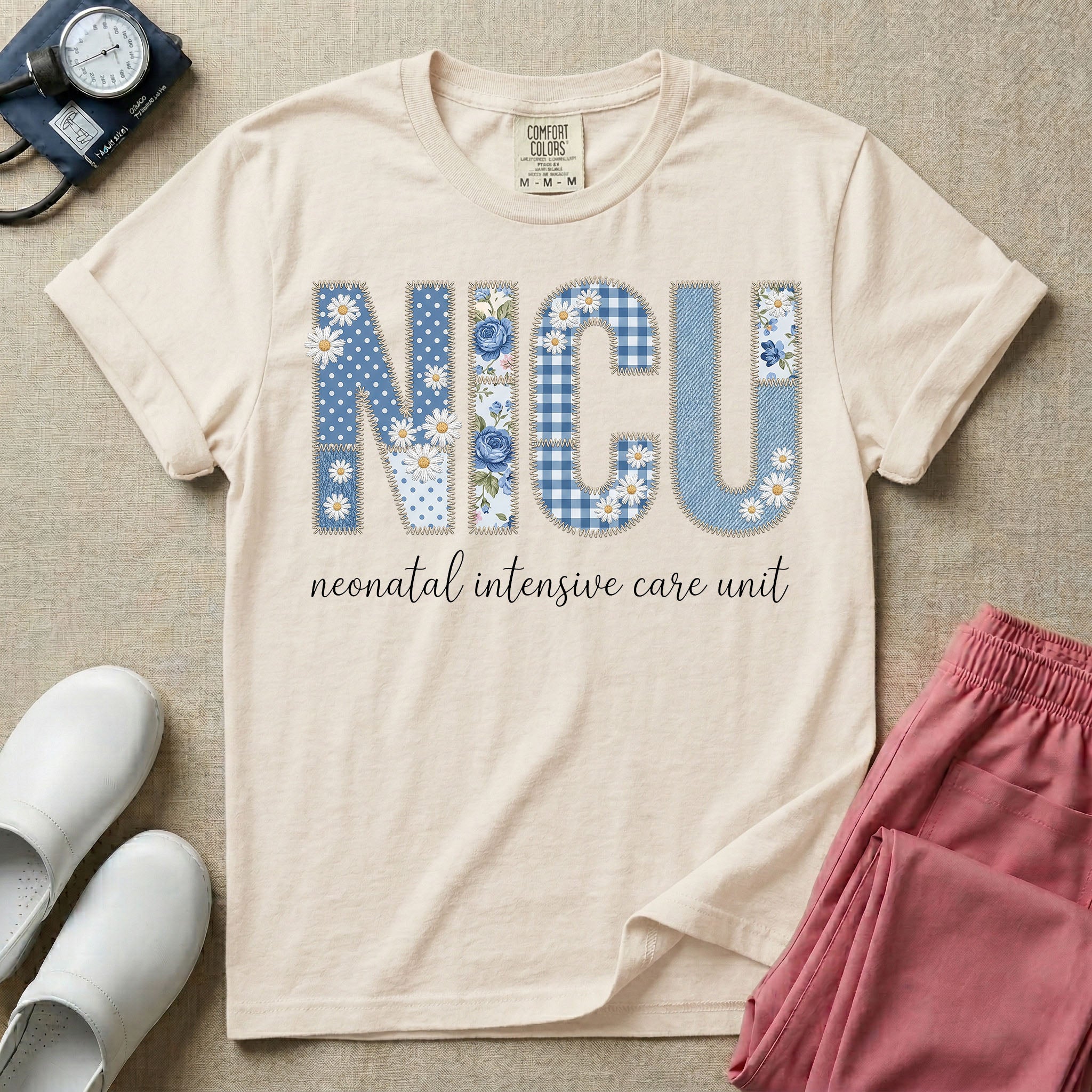 Neonatal Intensive Care Unit NICU nursing t-shirt featuring a faux-embroidery graphic of the letters NICU filled with blue floral and checkered patterns, positioned above the cursive text "neonatal intensive care unit".