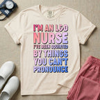 A humorous graphic tee for labor and delivery nurses featuring bold, gradient block lettering that reads "I'M AN L&D NURSE I'VE BEEN SQUIRTED BY THINGS YOU CAN'T PRONOUNCE".