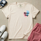 A minimalist postpartum nursing t-shirt featuring a small left chest graphic of two baby footprints, one pink and one blue, with the cursive white text "Mother Baby" written across them.