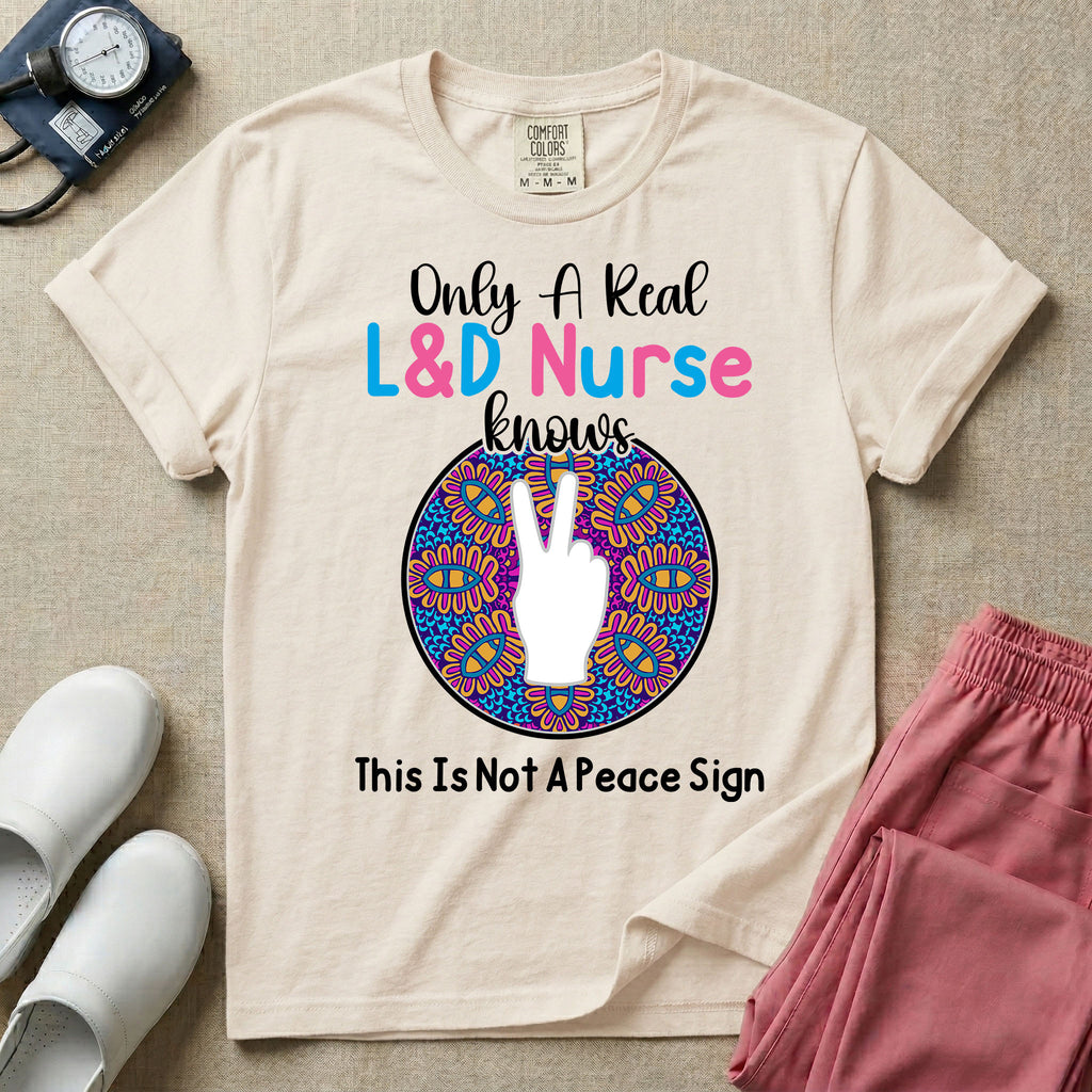 A humorous Labor and Delivery nurse graphic featuring a hand holding up two fingers inside a colorful boho mandala pattern, surrounded by text that reads Only A Real L&D Nurse Knows above and This Is Not A Peace Sign below.