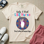 A humorous Labor and Delivery nurse graphic featuring a hand holding up two fingers inside a colorful boho mandala pattern, surrounded by text that reads Only A Real L&D Nurse Knows above and This Is Not A Peace Sign below.
