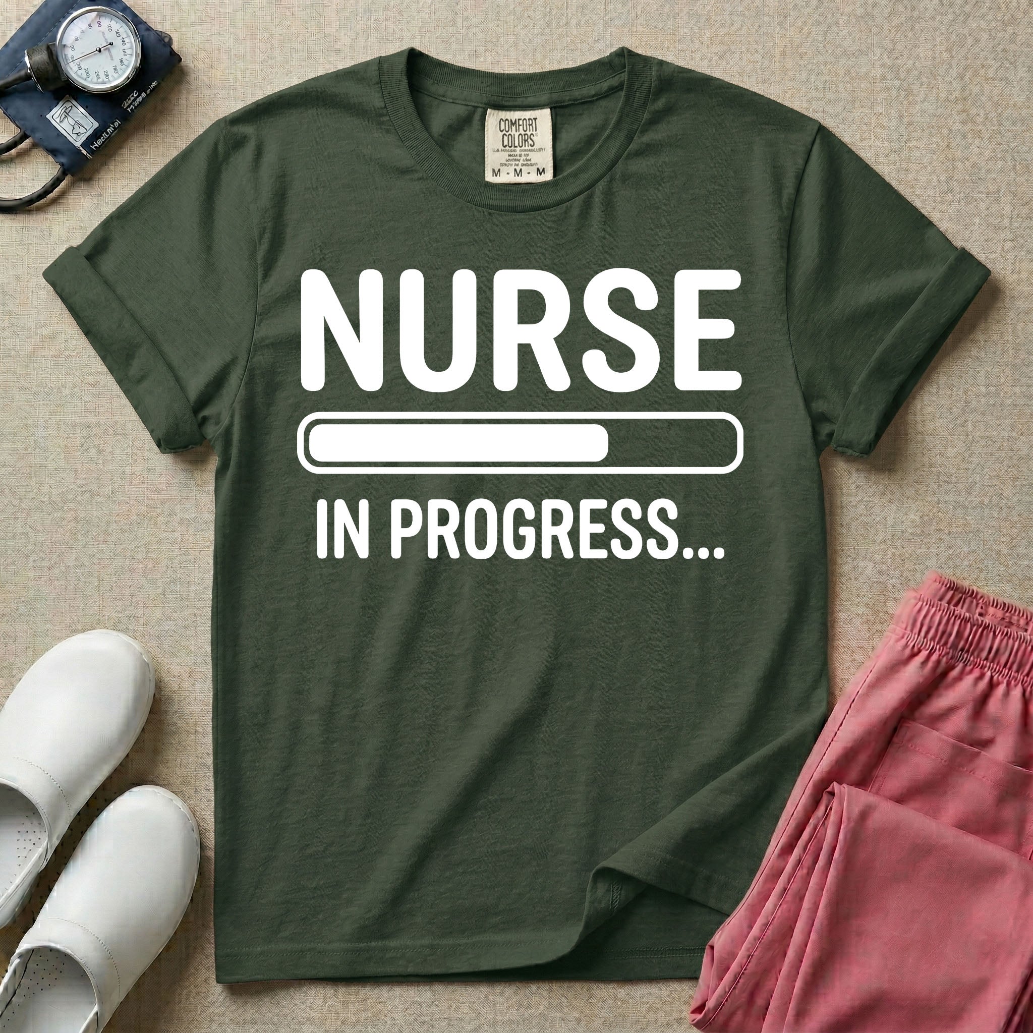 General nursing student t-shirt featuring a white loading bar graphic and the text "NURSE IN PROGRESS..." on a dark gray garment, in moss color.