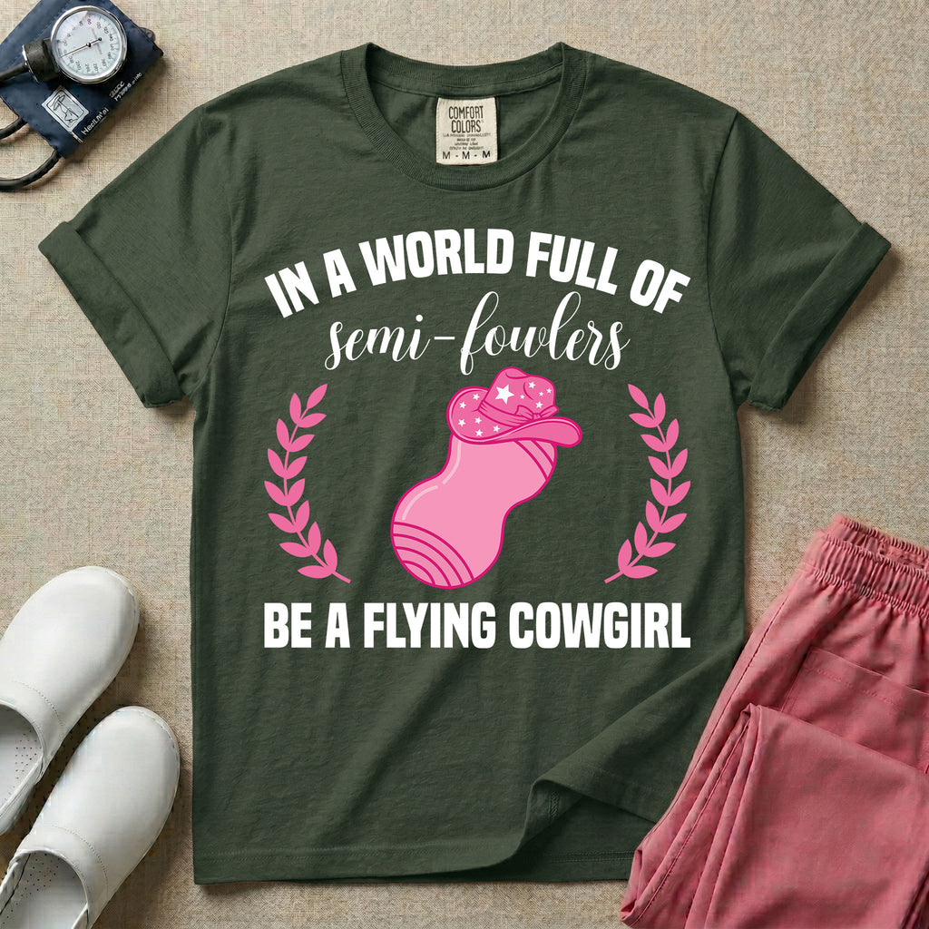 A humorous graphic tee for labor and delivery nurses featuring an illustration of a peanut ball wearing a cowboy hat, framed by laurel branches, along with the text "IN A WORLD FULL OF semi-fowlers BE A FLYING COWGIRL".