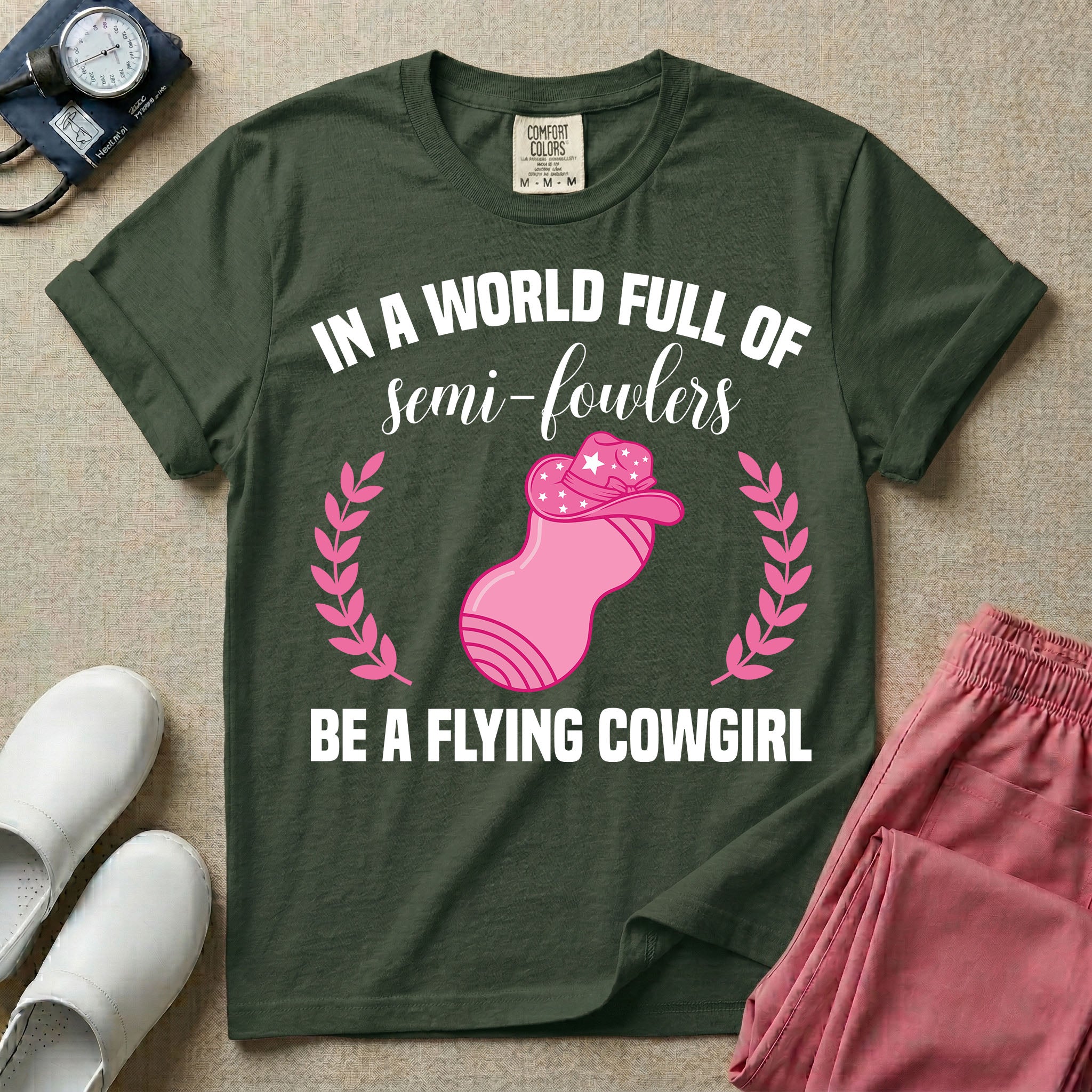 A humorous graphic tee for labor and delivery nurses featuring an illustration of a peanut ball wearing a cowboy hat, framed by laurel branches, along with the text "IN A WORLD FULL OF semi-fowlers BE A FLYING COWGIRL".