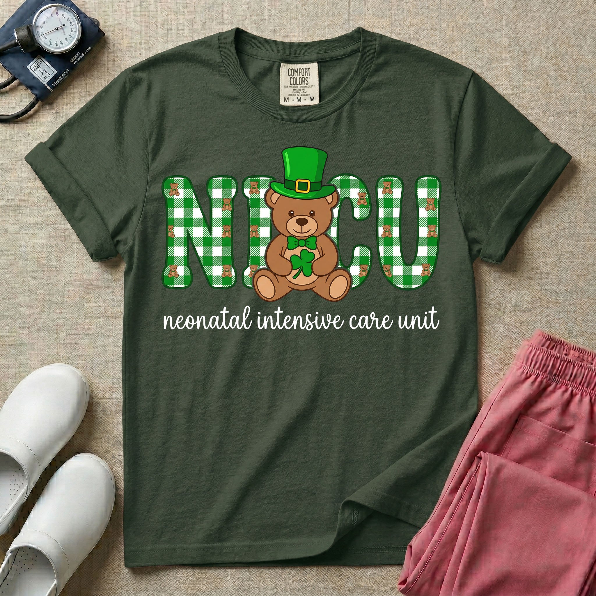 A graphic for a Neonatal Intensive Care Unit featuring the word 'NICU' in green and white plaid patterned letters, with a cute brown teddy bear wearing a leprechaun hat and holding a shamrock sitting in the middle, and the cursive text 'neonatal intensive care unit' underneath.