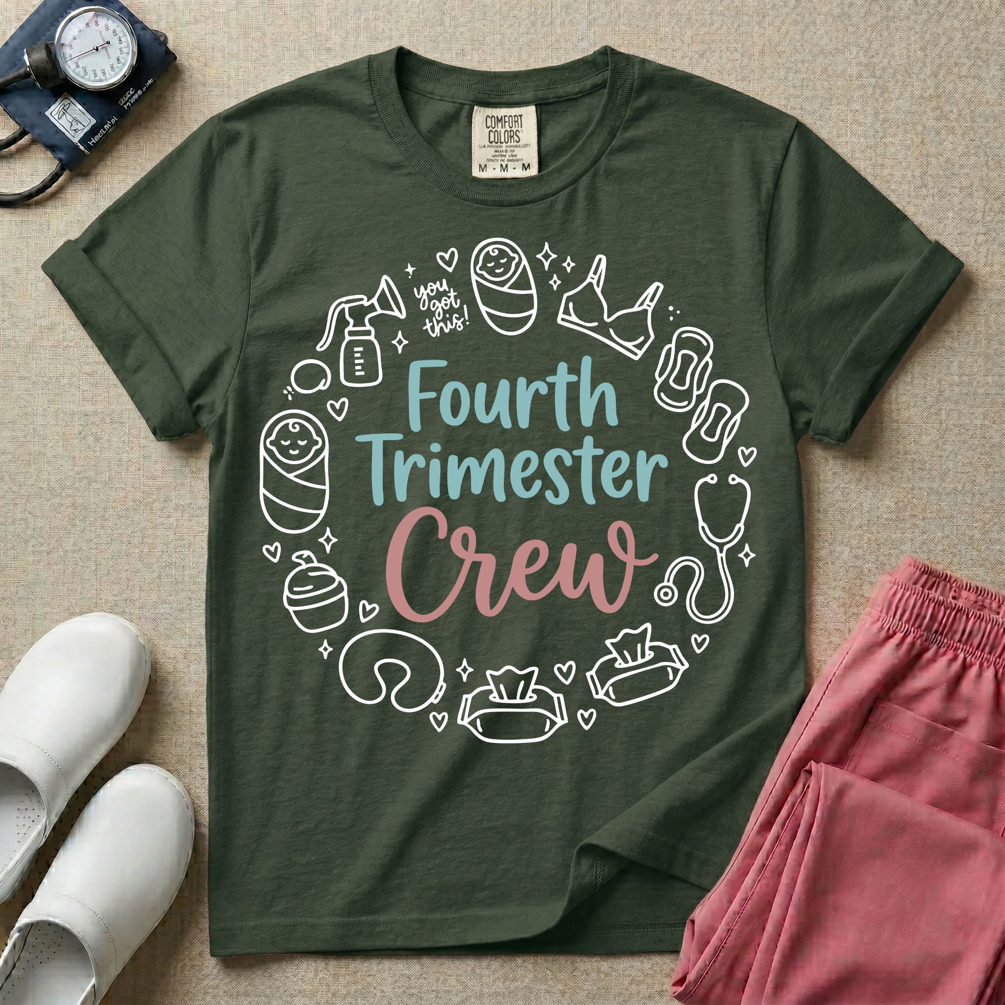 A postpartum nursing t-shirt featuring the stacked text "Fourth Trimester Crew" in blue and pink retro fonts, surrounded by a circular border of white minimalist line drawings depicting newborn and postpartum care items including a breast pump, swaddled baby, maternity bra, maxi pad, stethoscope, wipes, and a nursing pillow.