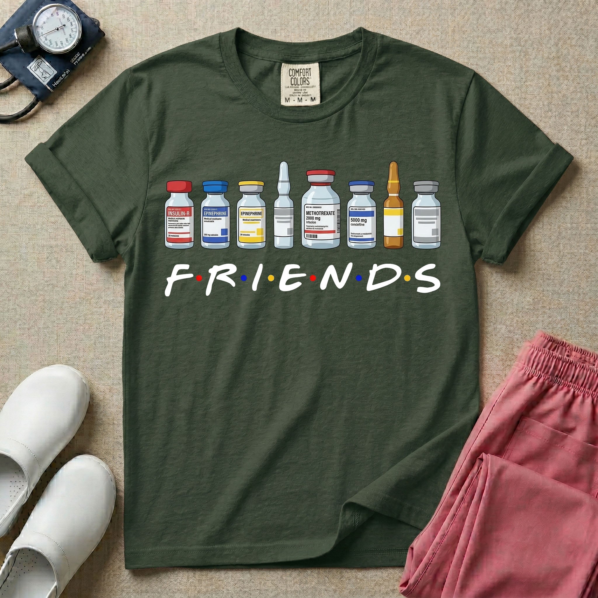 A humorous retro-style t-shirt for nurses featuring a row of seven different medical vials and medicine ampules lined up above the word "FRIENDS", which is styled with colored dots between the letters to resemble the classic television show logo.