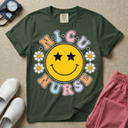 A t-shirt featuring a large yellow smiley face with star eyes surrounded by smiley face daisies and the text N.I.C.U. NURSE in pastel retro bubble lettering.