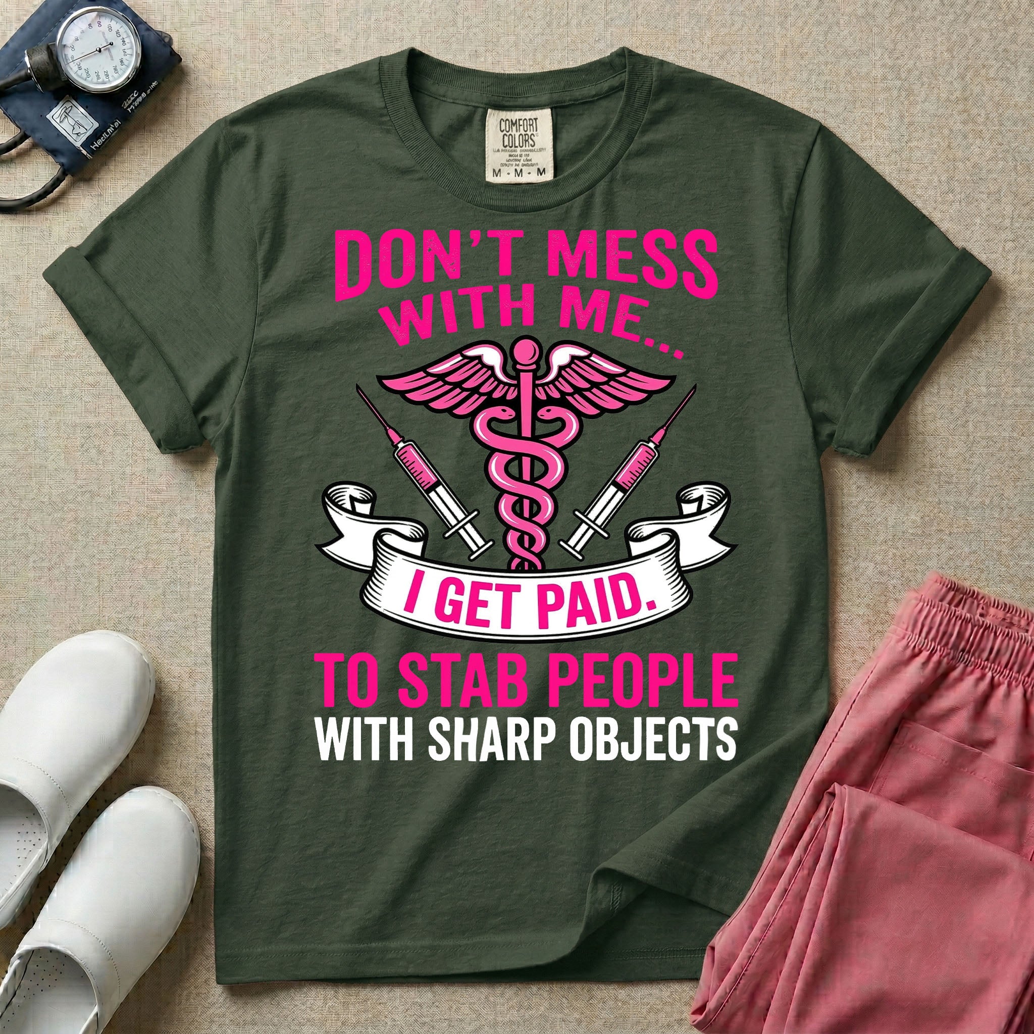 General nursing and ER t-shirt featuring a pink and black caduceus medical symbol flanked by two syringes alongside the humorous text "DON'T MESS WITH ME... I GET PAID TO STAB PEOPLE WITH SHARP OBJECTS".