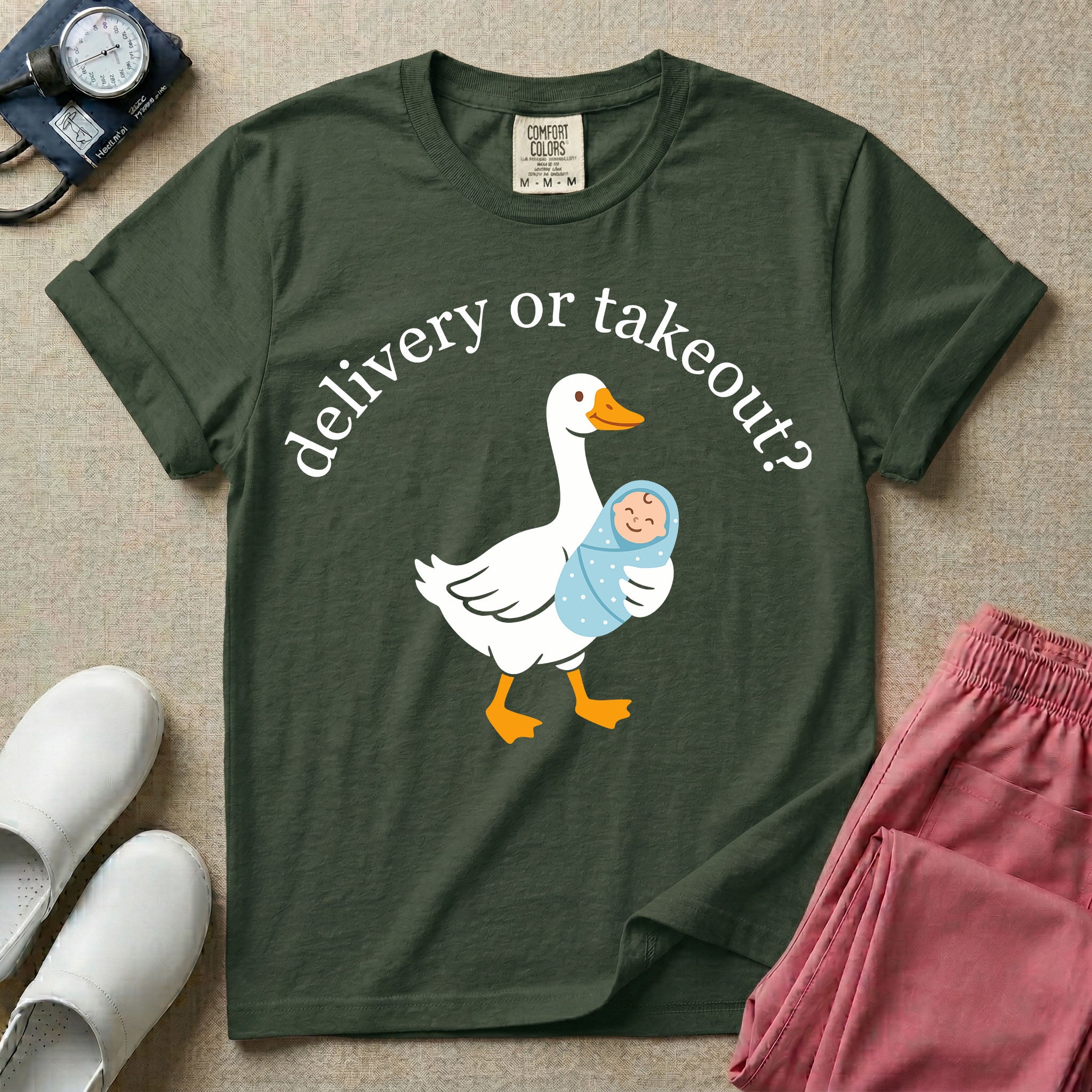 A funny L&D nursing t-shirt featuring a graphic of a white silly goose carrying a baby in a blue swaddle in its beak, surrounded by the humorous arched text "delivery or takeout?".