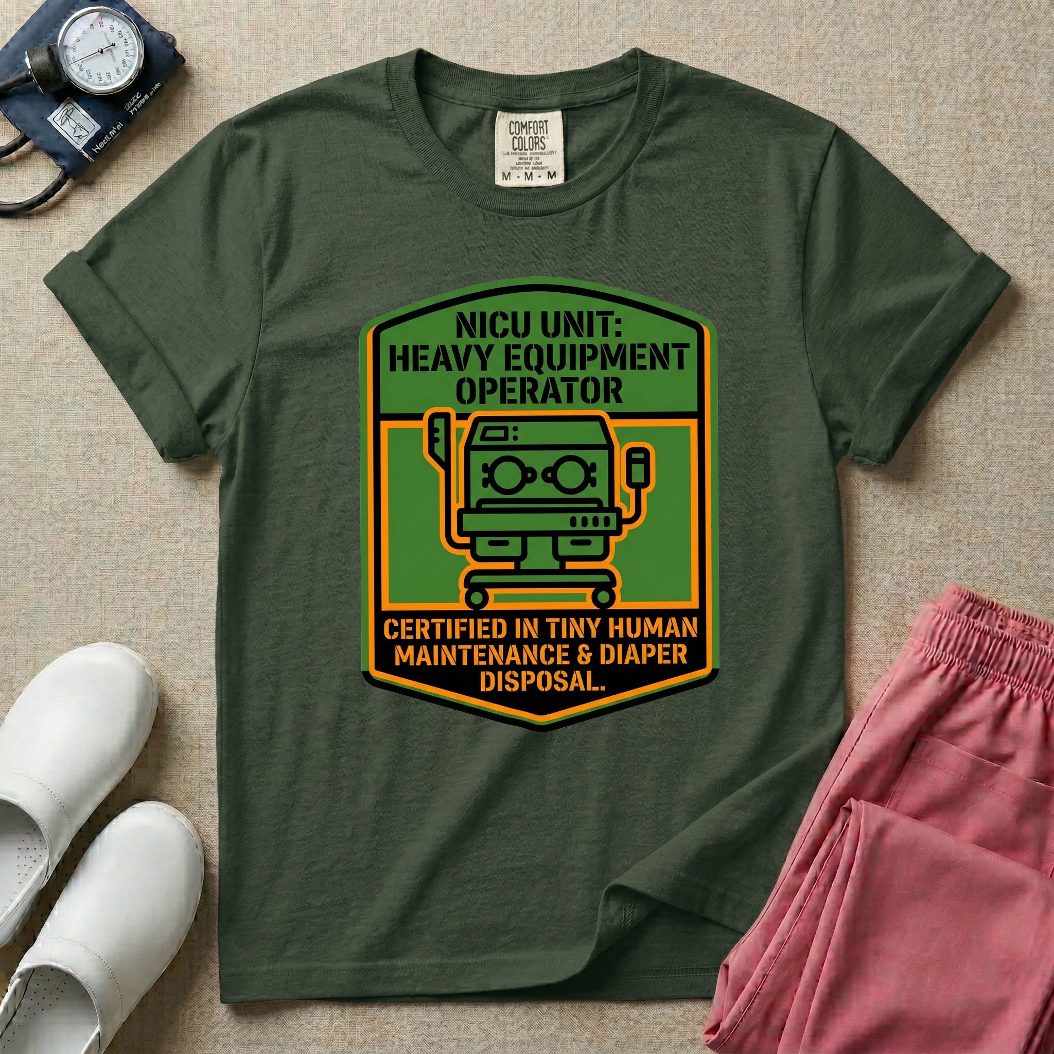 A graphic resembling a patch with green borders and orange inner sections featuring an illustration of a medical incubator in the center, with the text 'NICU UNIT: HEAVY EQUIPMENT OPERATOR' at the top and 'CERTIFIED IN TINY HUMAN MAINTENANCE & DIAPER DISPOSAL' at the bottom.