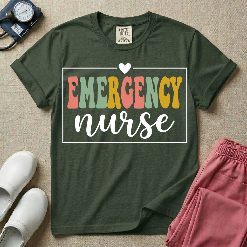 A retro-style t-shirt for emergency room nurses featuring the word "EMERGENCY" in colorful, vintage lettering above the word "nurse" in a delicate white script font, framed by a thin white rectangular border with a small heart at the top center.