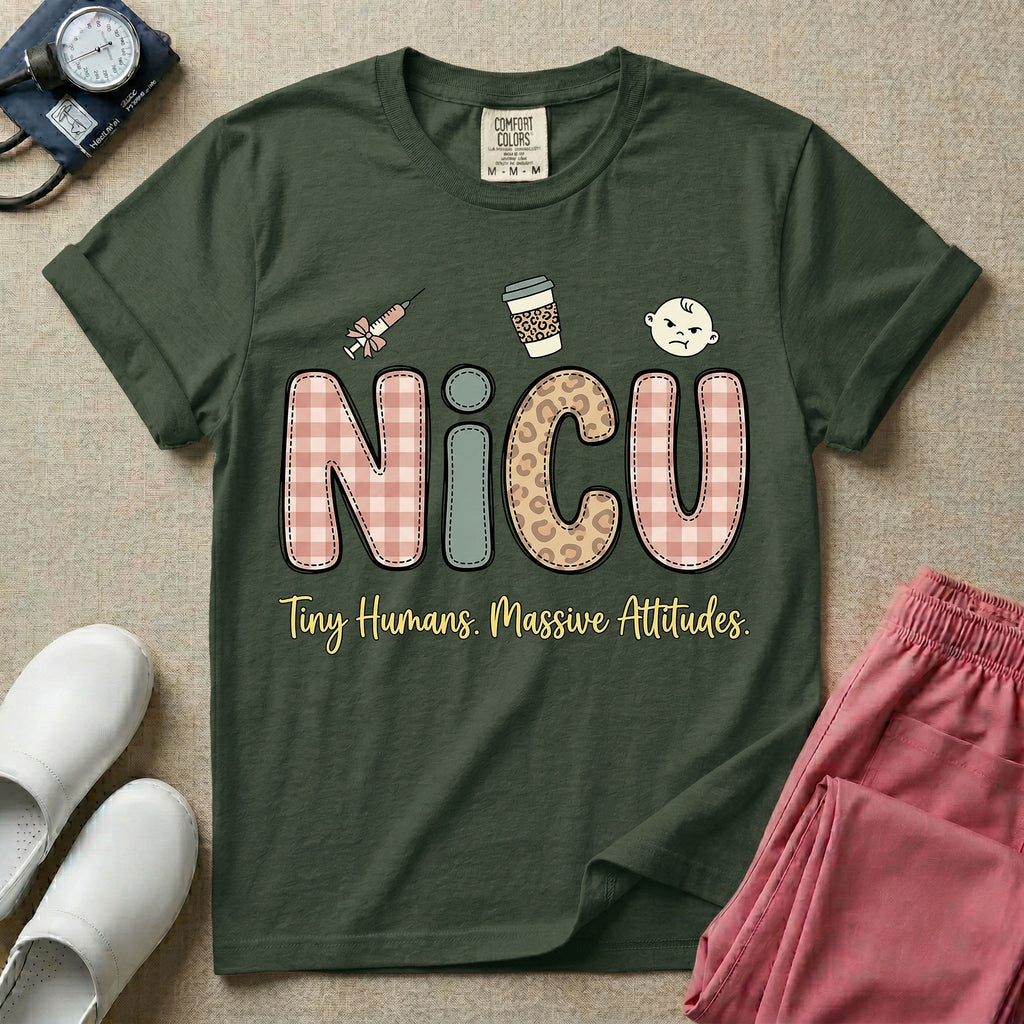 A humorous t-shirt for NICU nurses featuring the large text "NICU" in plaid and patterned letters with the phrase "Tiny Humans. Massive Attitudes." underneath, accompanied by small cute graphics of a syringe, an iced coffee cup, and a baby's face.
