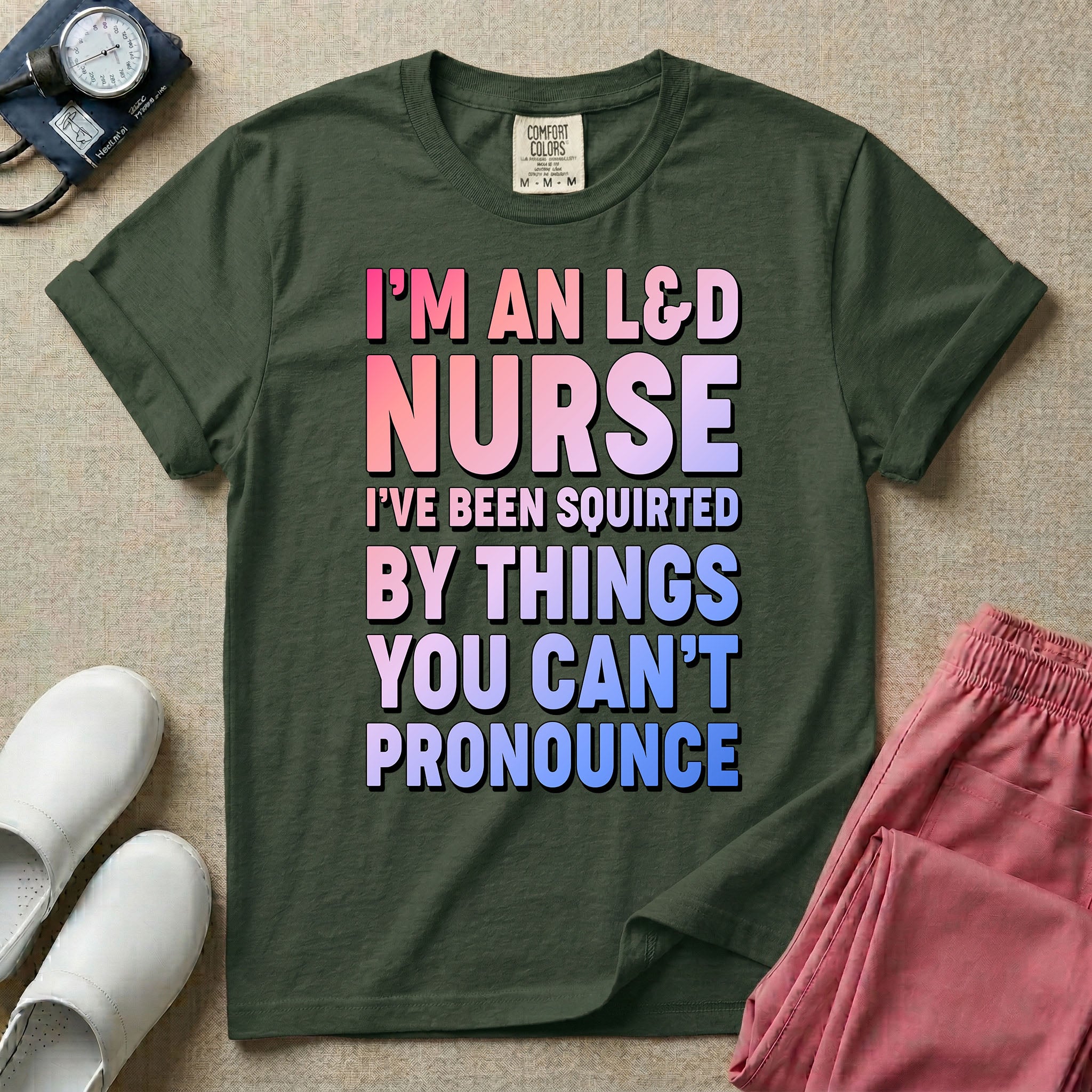 A humorous graphic tee for labor and delivery nurses featuring bold, gradient block lettering that reads "I'M AN L&D NURSE I'VE BEEN SQUIRTED BY THINGS YOU CAN'T PRONOUNCE".