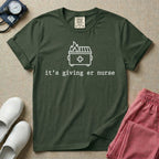 A funny minimalist ER nursing t-shirt featuring a simple white line drawing of a dumpster on fire with a medical cross on it, sitting above the lower-case typewriter text "it's giving er nurse".