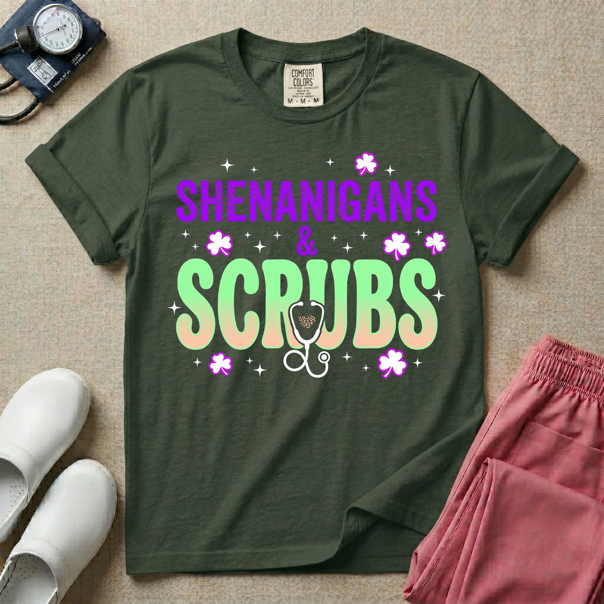 General nursing St. Patrick's Day t-shirt featuring a retro wavy font with the text "SHENANIGANS & SCRUBS" surrounded by shamrock graphics and a stethoscope.