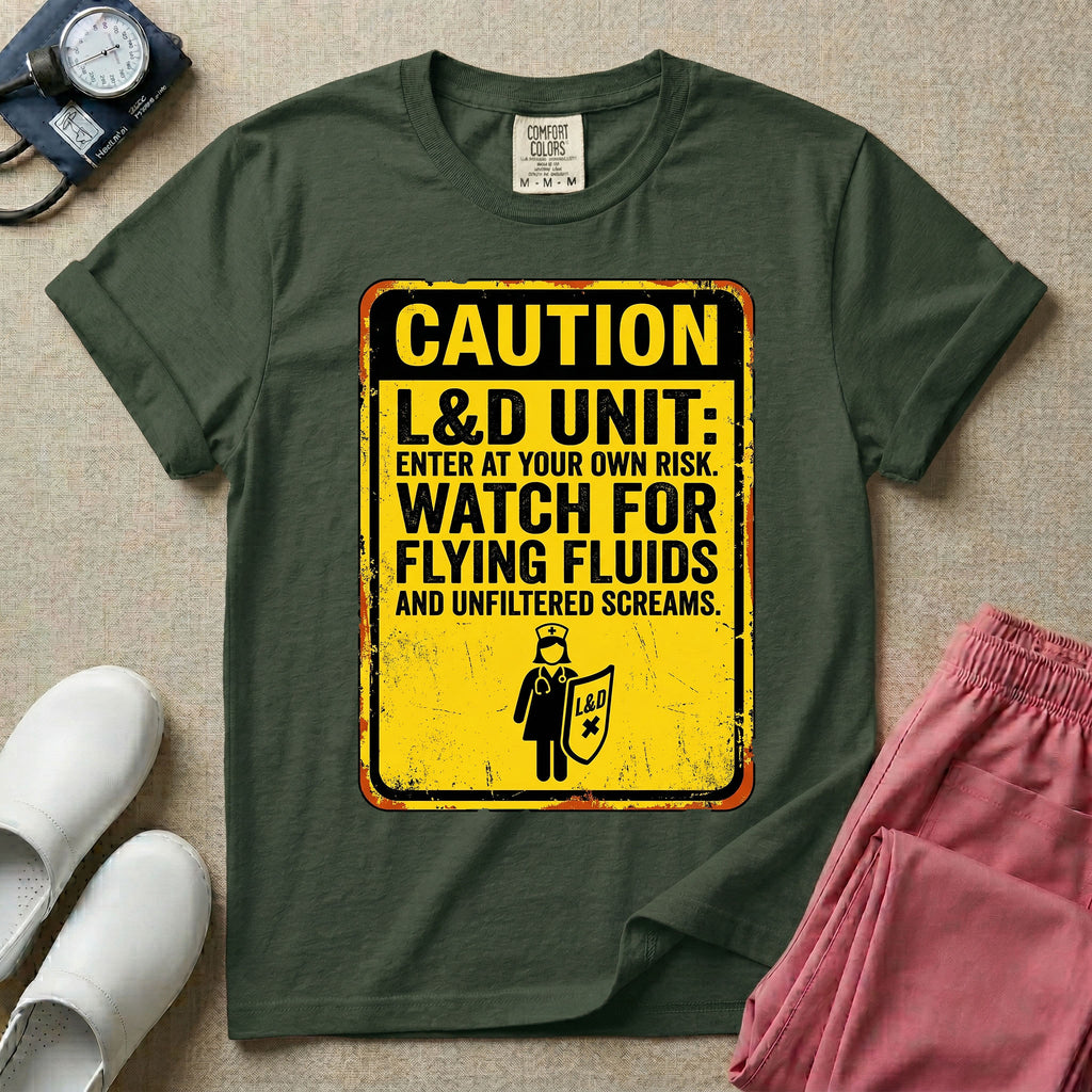 A humorous graphic tee for labor and delivery nurses featuring a distressed caution sign design with the text "CAUTION L&D UNIT: ENTER AT YOUR OWN RISK. WATCH FOR FLYING FLUIDS AND UNFILTERED SCREAMS." above a stick figure nurse holding a shield.