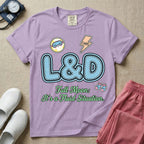 A humorous Labor and Delivery nurse graphic featuring large, light blue varsity-style letters spelling L&D with a pink dashed outline, surrounded by small patch-like icons of a baby and a lightning bolt, sitting above cursive text that reads Full Moon: It's a Fluid Situation.