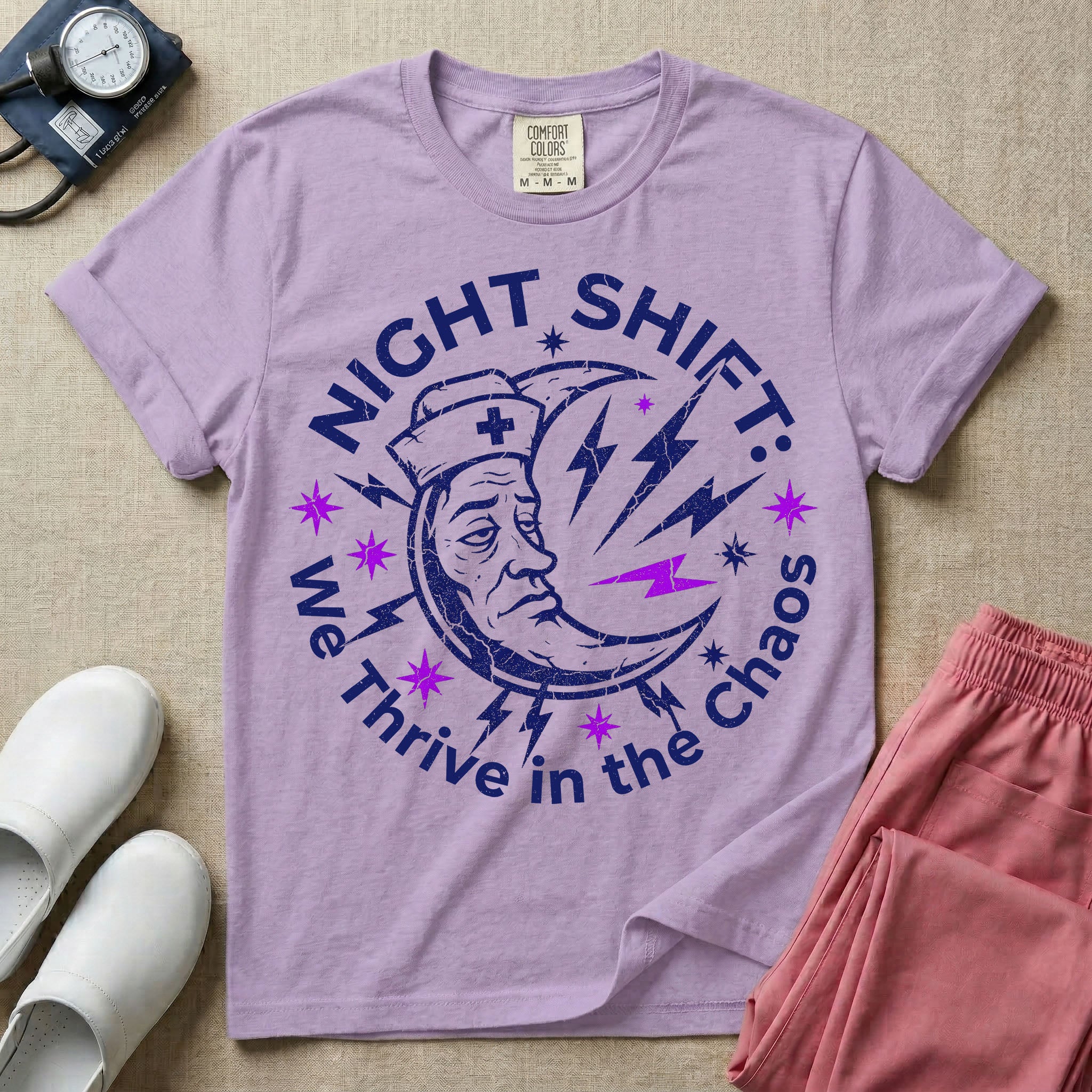 General nursing night shift nurse t-shirt with a retro purple moon wearing a nurse cap and we thrive in the chaos graphic in orchid color.