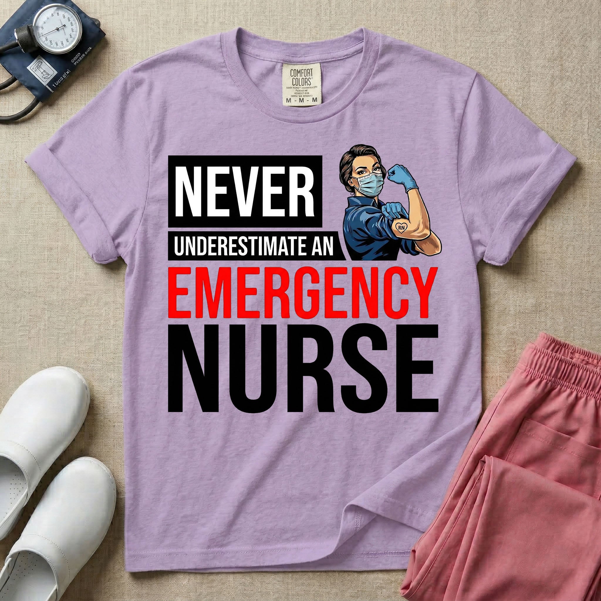 A retro ER nursing t-shirt featuring the bold text "NEVER UNDERESTIMATE AN EMERGENCY NURSE" alongside a vintage graphic of a masked nurse flexing her arm in a classic Rosie the Riveter pose