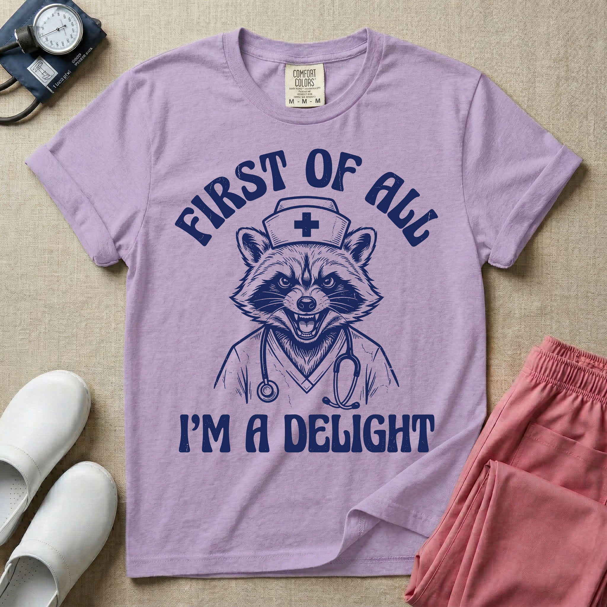 A humorous graphic of a raccoon dressed in a nursing cap and scrub jacket with a stethoscope, with the text "FIRST OF ALL I'M A DELIGHT", in orchid color.