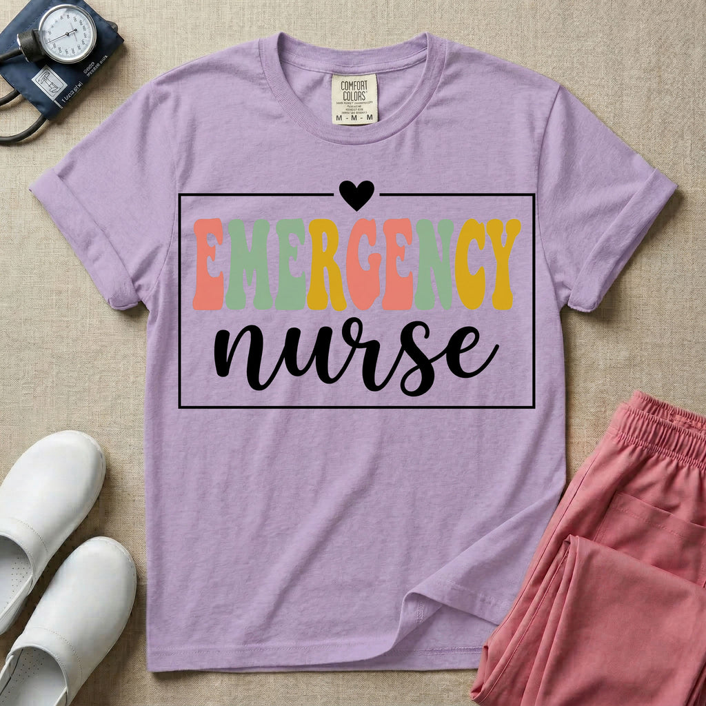 A retro-style t-shirt for emergency room nurses featuring the word "EMERGENCY" in colorful, vintage lettering above the word "nurse" in a delicate white script font, framed by a thin white rectangular border with a small heart at the top center.