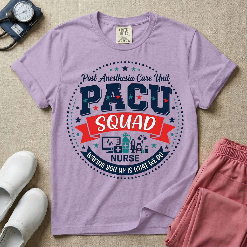 A t-shirt featuring a circular badge design with the text PACU SQUAD in block letters, medical icons like a heart monitor and stethoscope, and the phrase Waking You Up Is What We Do.