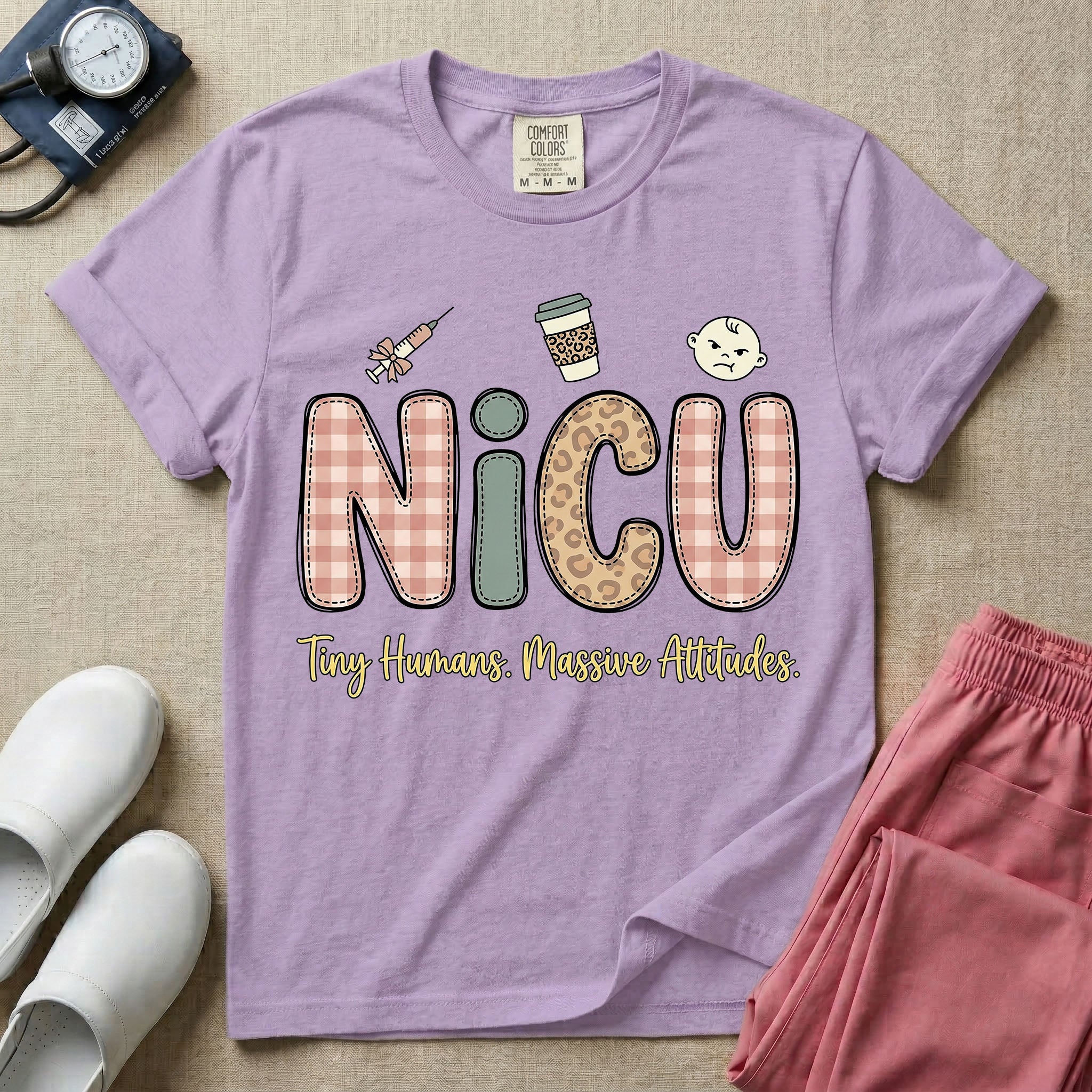 A humorous t-shirt for NICU nurses featuring the large text "NICU" in plaid and patterned letters with the phrase "Tiny Humans. Massive Attitudes." underneath, accompanied by small cute graphics of a syringe, an iced coffee cup, and a baby's face.