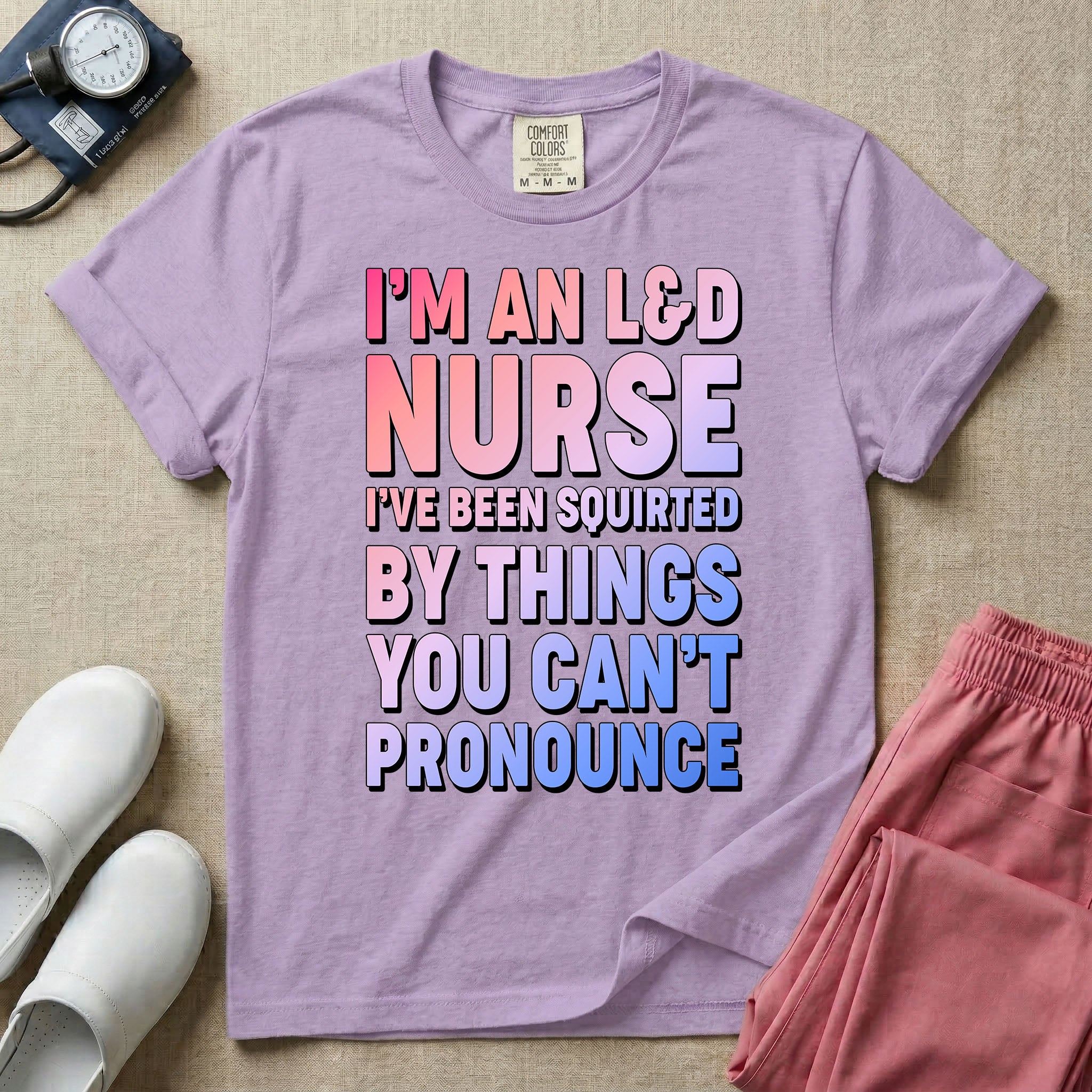 A humorous graphic tee for labor and delivery nurses featuring bold, gradient block lettering that reads "I'M AN L&D NURSE I'VE BEEN SQUIRTED BY THINGS YOU CAN'T PRONOUNCE".