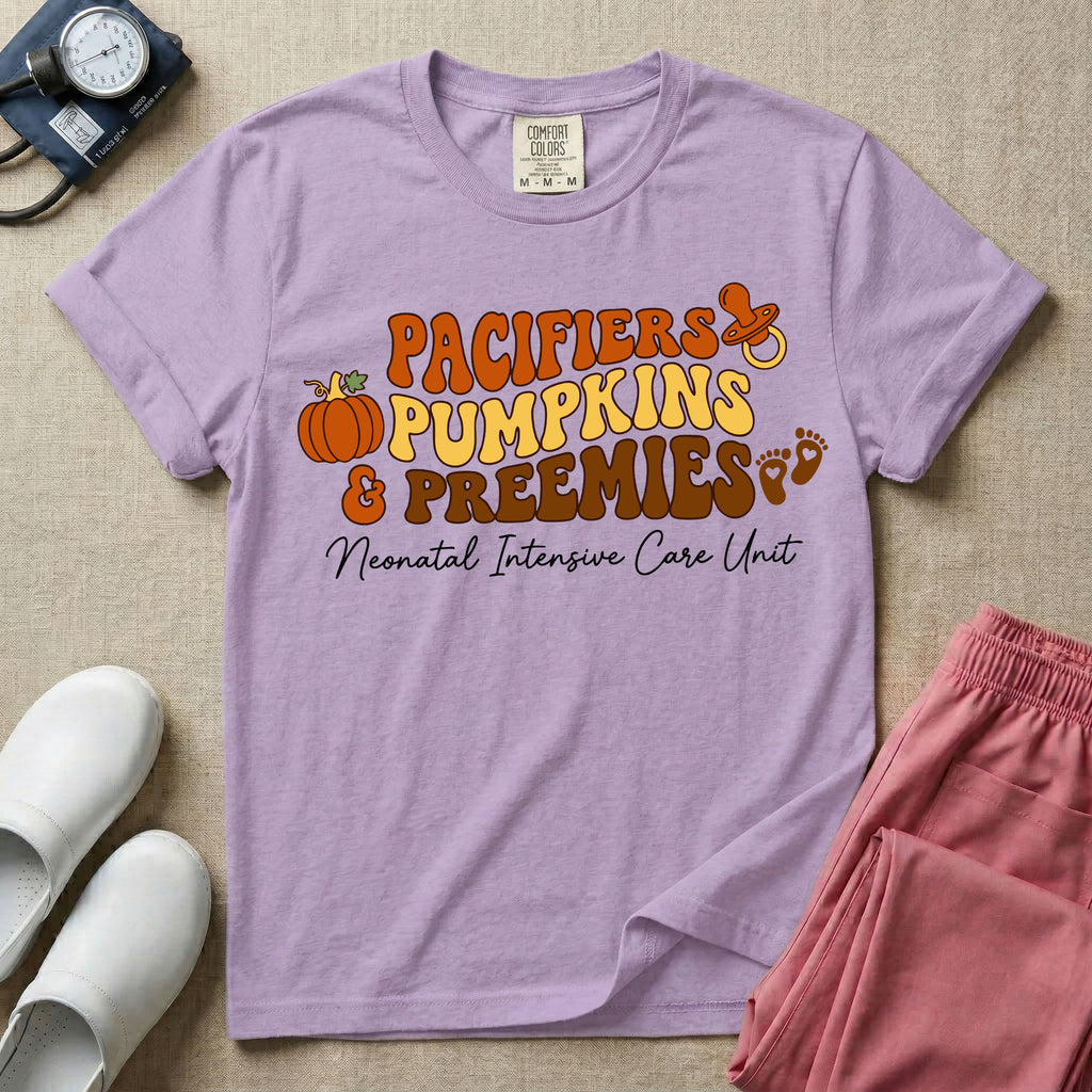 A t-shirt featuring the stacked text PACIFIERS PUMPKINS & PREEMIES in wavy orange, yellow, and brown retro lettering decorated with a pumpkin, pacifier, and baby footprints, with Neonatal Intensive Care Unit written in cursive below.