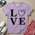 A minimalist nursing t-shirt featuring the word LOVE stacked in large white serif letters, with the letter O replaced by a white stethoscope shaped like a heart containing two small baby footprints, one pink and one blue.