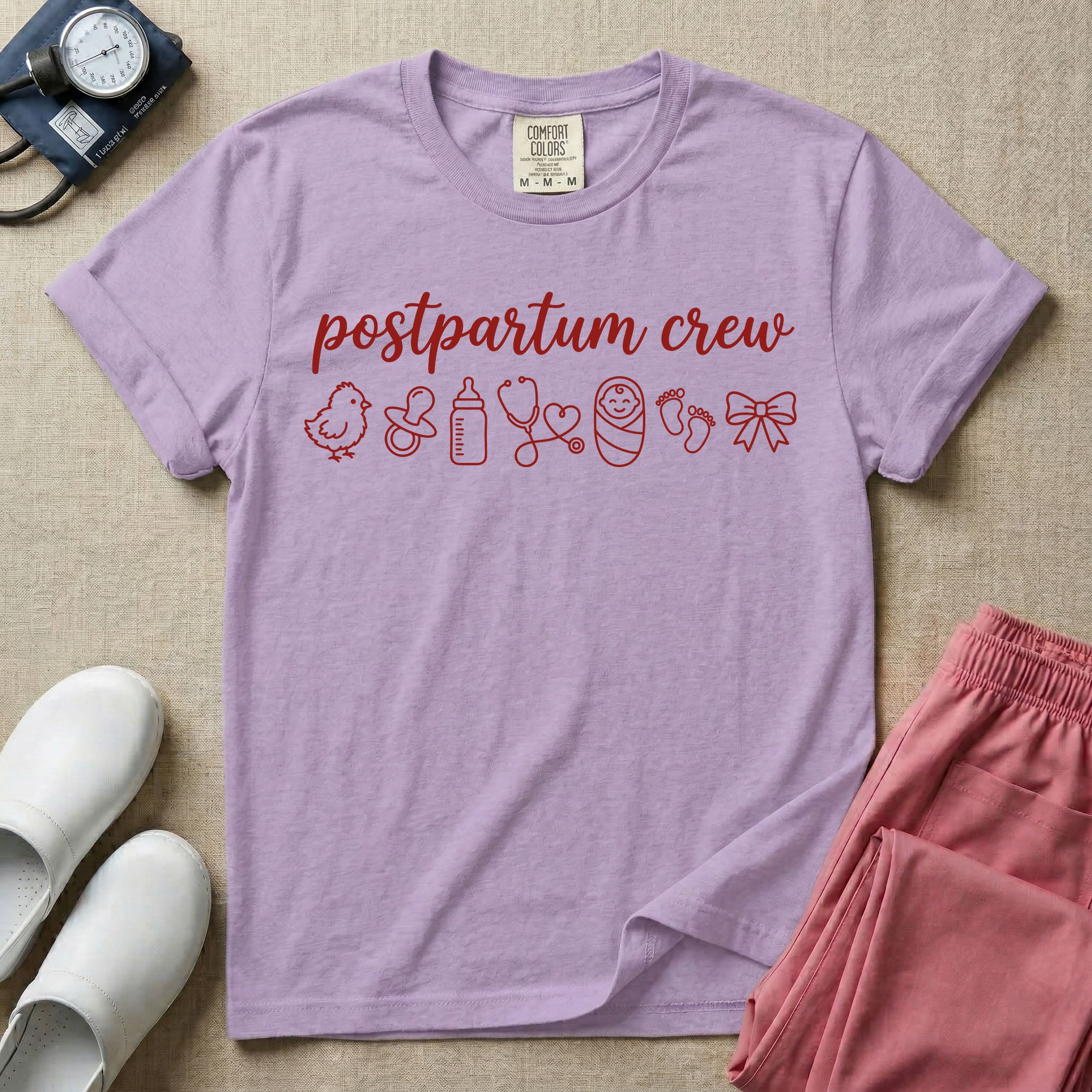 A t-shirt featuring the lowercase text postpartum crew in a cursive script font above a horizontal row of minimalist line-art icons including a baby chick, a pacifier, a baby bottle, a heart-shaped stethoscope, a swaddled baby, baby footprints, and a ribbon bow.
