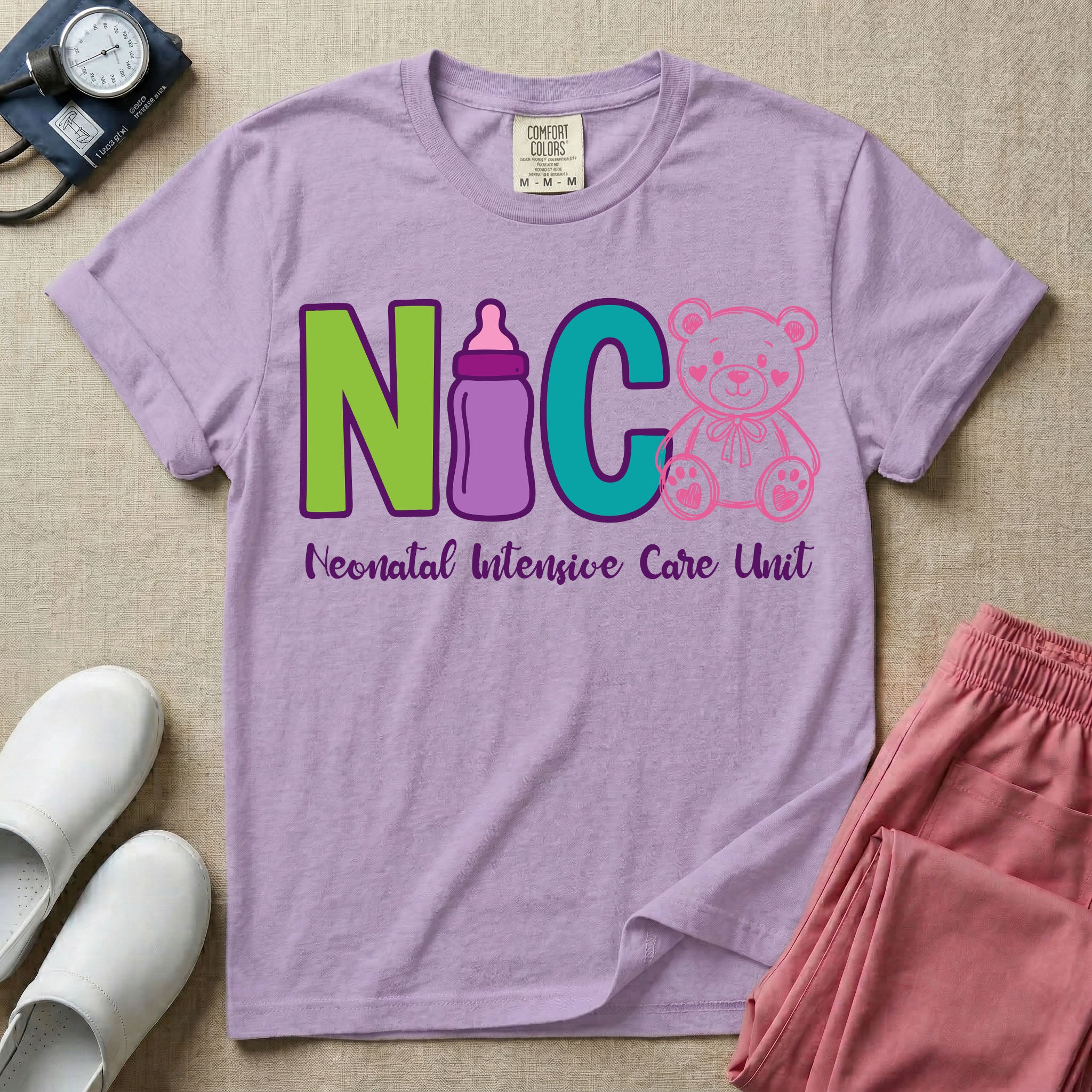 A t-shirt featuring the acronym NICU creatively spelled out using a green letter N, a purple baby bottle, a teal letter C, and a pink outlined teddy bear, with the words Neonatal Intensive Care Unit written in cursive script below.