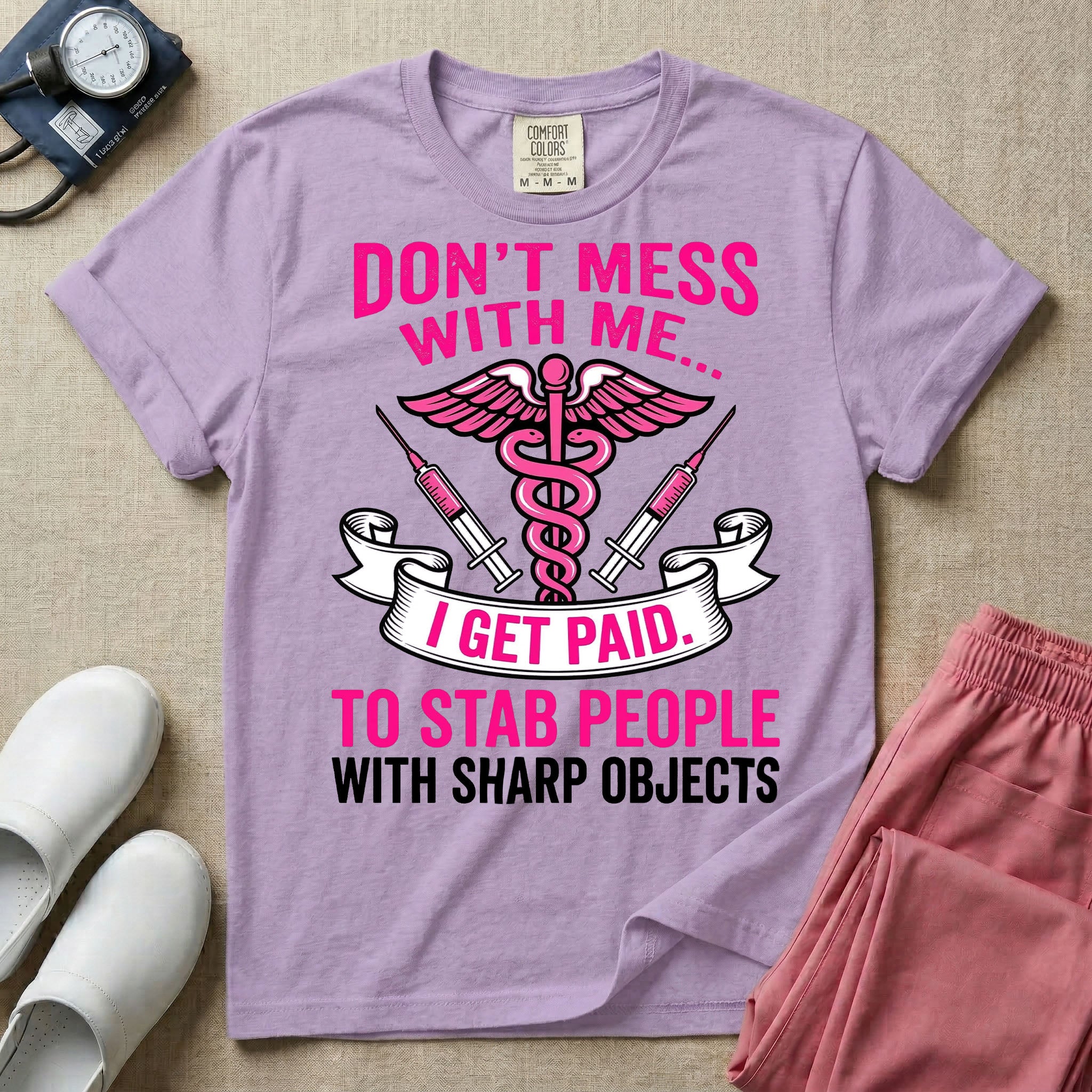 General nursing and ER t-shirt featuring a pink and black caduceus medical symbol flanked by two syringes alongside the humorous text "DON'T MESS WITH ME... I GET PAID TO STAB PEOPLE WITH SHARP OBJECTS".