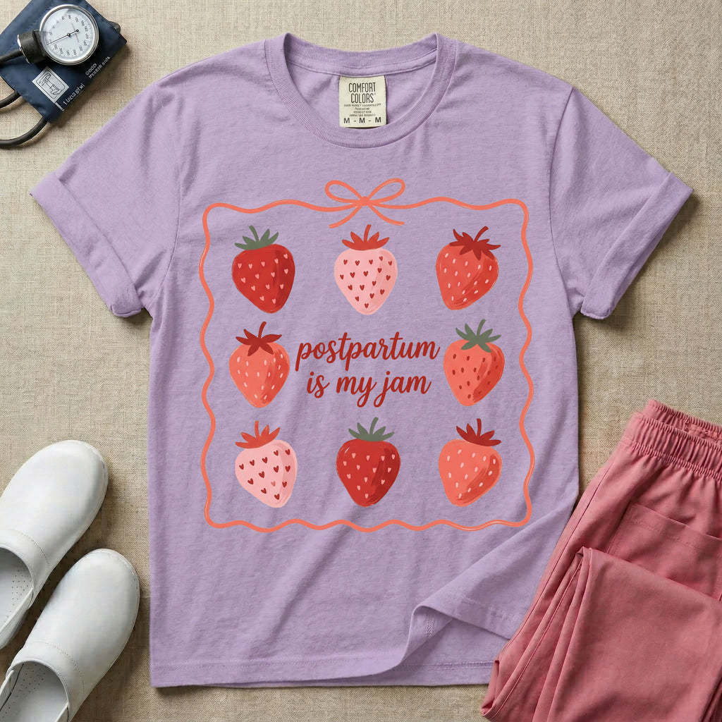 A funny and cute postpartum nursing t-shirt featuring the pun text "postpartum is my jam" surrounded by a graphic of red and pink strawberries, enclosed in a decorative wavy border with a bow at the top.