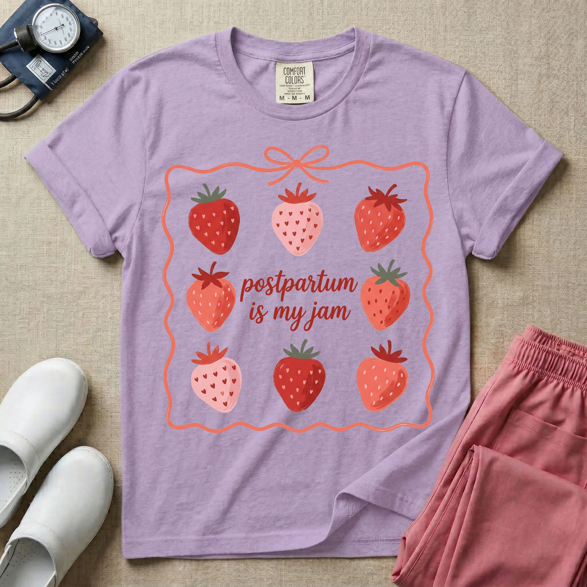 A funny and cute postpartum nursing t-shirt featuring the pun text "postpartum is my jam" surrounded by a graphic of red and pink strawberries, enclosed in a decorative wavy border with a bow at the top.