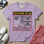A humorous and retro graphic tee for labor and delivery nurses featuring a vintage nurse illustration alongside the text "FIELD GUIDE TO L&D", "STANCE: WIDE", "REFLEXES: SHARP", "PATIENCE: NON-EXISTENT", and "CAUTION: HIGH PROBABILITY OF UNPLANNED HYDROMASSAGE".