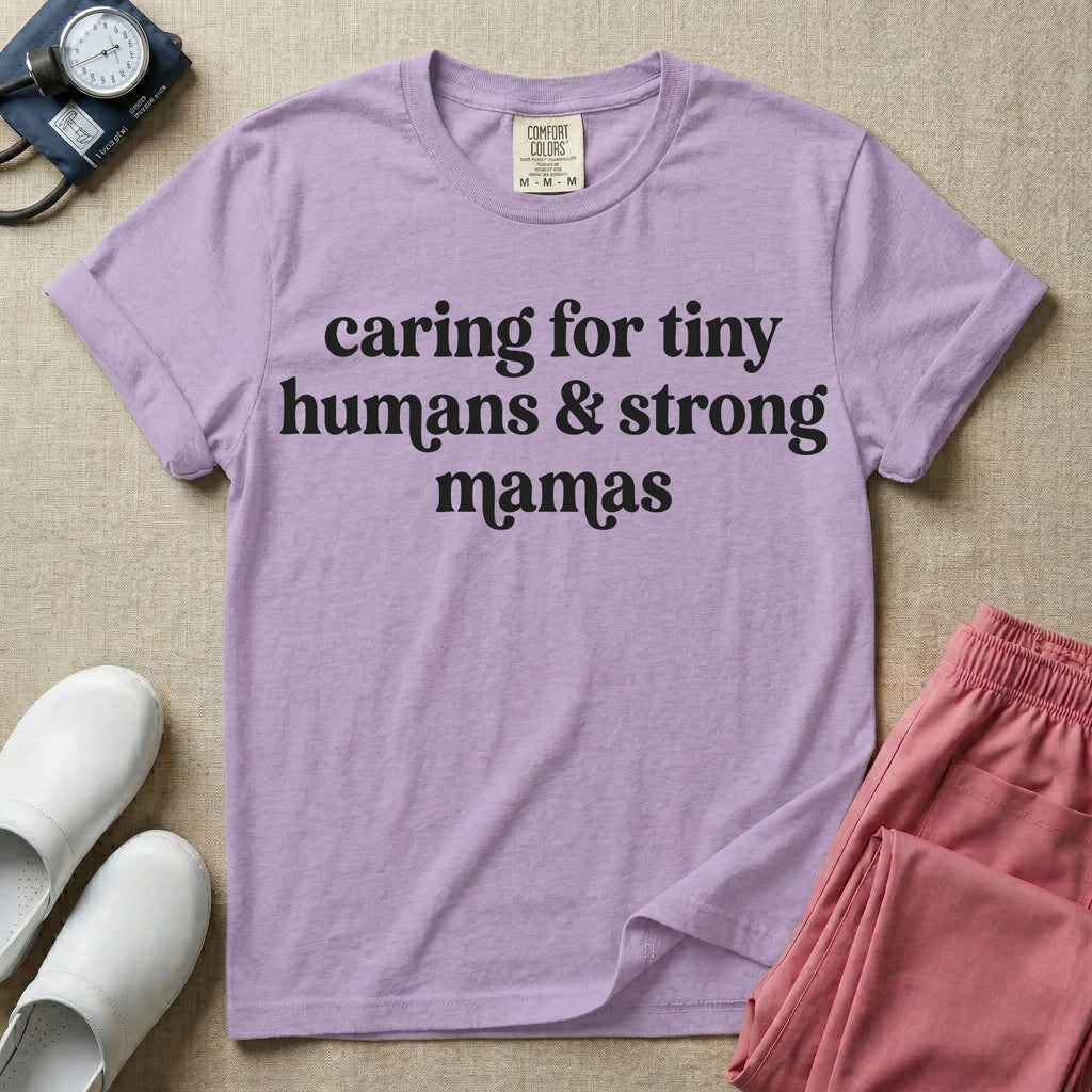 A minimalist nursing t-shirt featuring the text "caring for tiny humans & strong mamas" written in a retro white serif font.