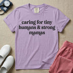 A minimalist nursing t-shirt featuring the text "caring for tiny humans & strong mamas" written in a retro white serif font.