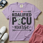 A funny pediatric intensive care nursing t-shirt featuring the pun text "KOALIFIED PICU nurse" with a cute koala graphic replacing the letter I in PICU, framed by decorative arrows and a pink medical cross.